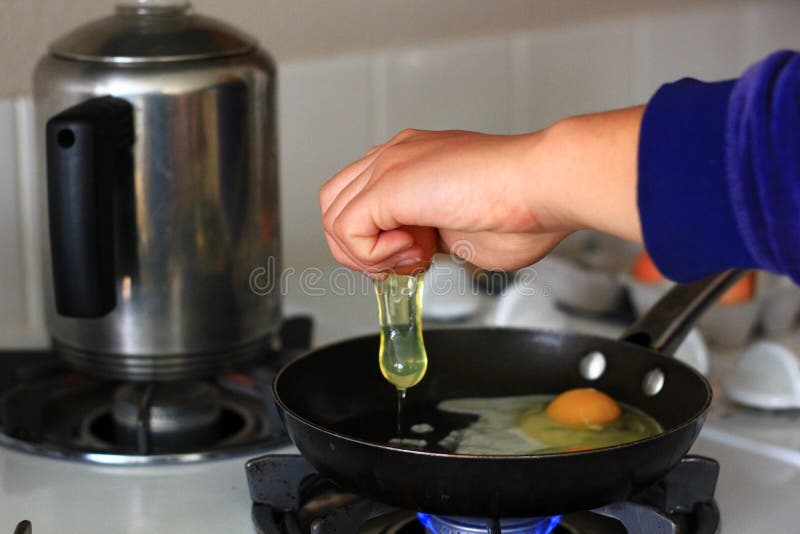 Personne faisant cuire des oeufs dans une casserole image stock Personne faisant cuire des oeufs dans une casserole image stock