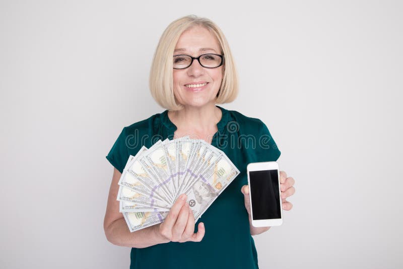 Personne féminine adulte tenant l'argent et le téléphone dans des ses mains dans un studio blanc photos libres de droits Personne féminine adulte tenant l'argent et le téléphone dans des ses mains dans un studio blanc photos libres de droits