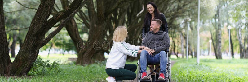 Personne handicapée en fauteuil roulant et deux femmes s'occupent de lui dans le parc. photos libres de droits