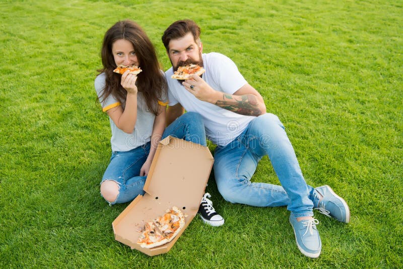 Personnes affam?es Bonheur simple Repas de fraude Couplez manger de la pizza détendant sur la pelouse verte la livraison d'alimen image stock Personnes affam?es Bonheur simple Repas de fraude Couplez manger de la pizza détendant sur la pelouse verte la livraison d'alimen image stock