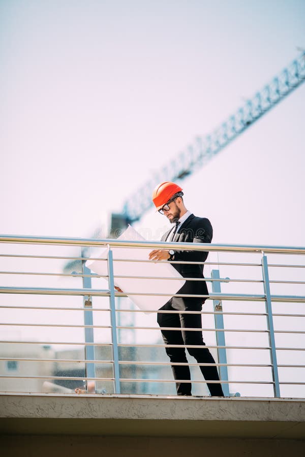Personnes de consultation d'ingénierie belle d'homme sur le chantier de construction tenant le modèle dans sa main Inspecteur des image stock Personnes de consultation d'ingénierie belle d'homme sur le chantier de construction tenant le modèle dans sa main Inspecteur des image stock