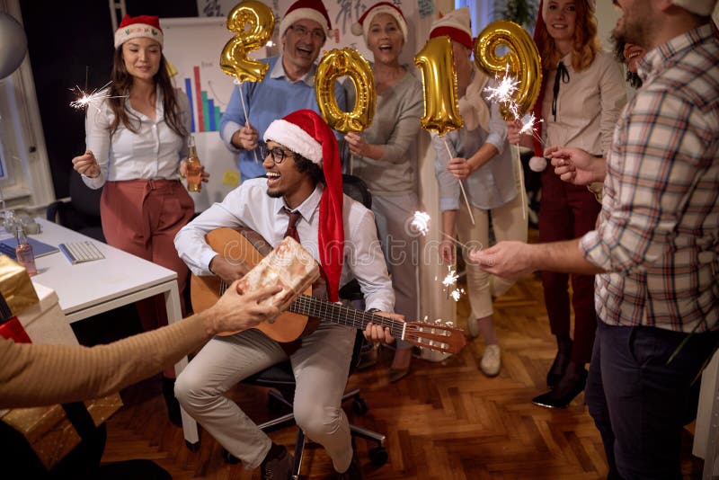 Personnes réussies de groupe d'affaires dans le chapeau de Santa à la partie de Noël célébrant avec la chanson photographie stock Personnes réussies de groupe d'affaires dans le chapeau de Santa à la partie de Noël célébrant avec la chanson photographie stock
