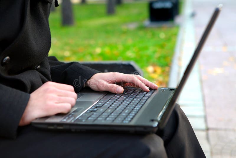 Person working on Laptop at the Autumn Park. Hands Closeup. Person working on Laptop at the Autumn Park. Hands Closeup