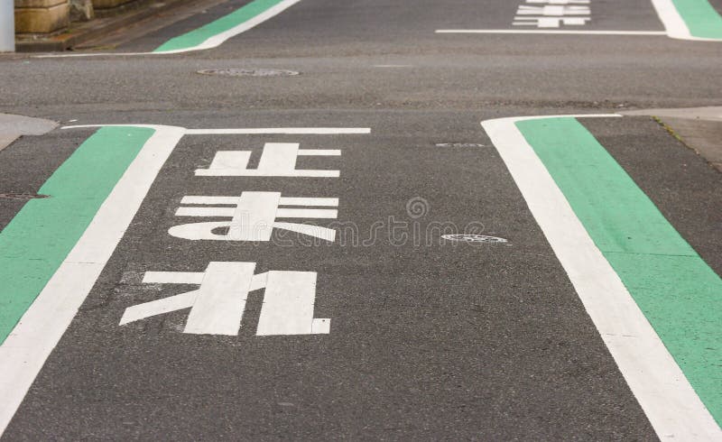 Perspective view of Japanese language word sign on black concrete street ground, mean as stop place to looking safety for who ride a bic or car. Perspective view of Japanese language word sign on black concrete street ground, mean as stop place to looking safety for who ride a bic or car