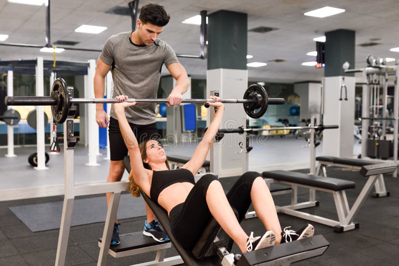 Persönlicher Trainer, welche einer jungen Frau hilft, Gewichte anzuheben lizenzfreie stockfotografie Persönlicher Trainer, welche einer jungen Frau hilft, Gewichte anzuheben lizenzfreie stockfotografie