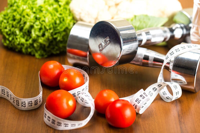 Pesas de gimnasia con la cinta métrica, verduras y fotografía de archivo Pesas de gimnasia con la cinta métrica, verduras y fotografía de archivo