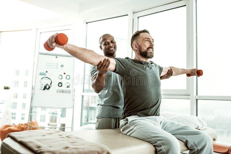 Pesas de gimnasia de elevación alegres de la persona masculina con placer imagen de archivo libre de regalías Pesas de gimnasia de elevación alegres de la persona masculina con placer imagen de archivo libre de regalías