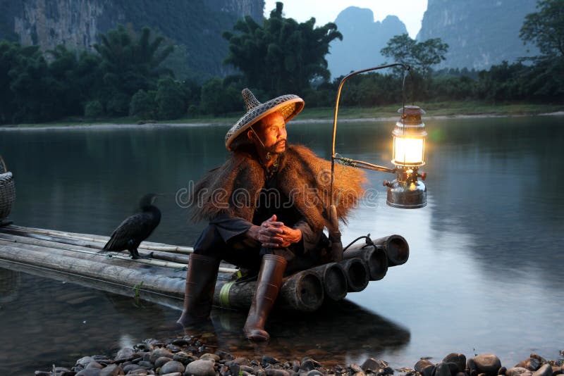 Pesca cinese dell'uomo con gli uccelli dei cormorani dentro fotografia stock libera da diritti Pesca cinese dell'uomo con gli uccelli dei cormorani dentro fotografia stock libera da diritti