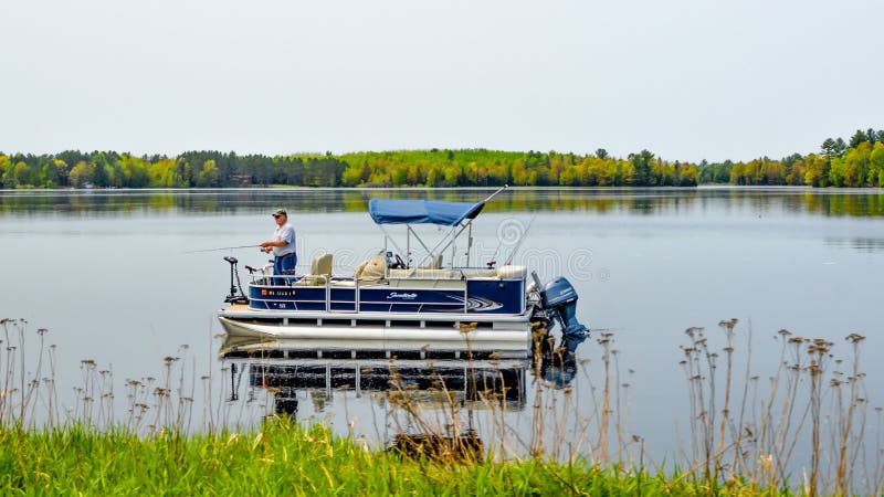 Pesca del hombre de un barco el pontón en el lago imagen de archivo libre de regalías
