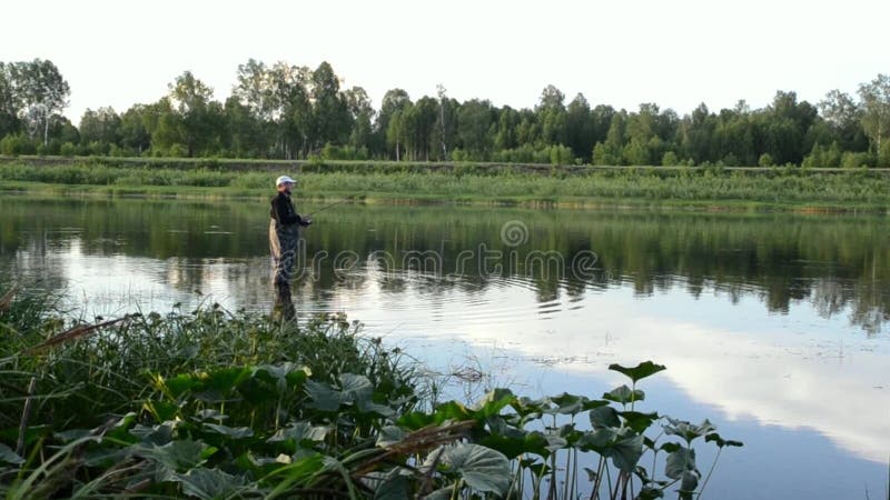 Pesca del pescador en un río tranquilo por la mañana