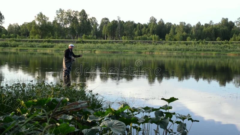 Pesca del pescador en un río tranquilo por la mañana
