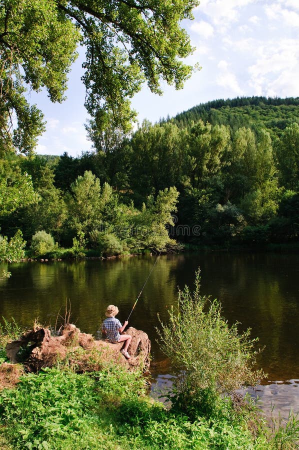 Pesca del ragazzo dal fiume immagine stock libera da diritti Pesca del ragazzo dal fiume immagine stock libera da diritti