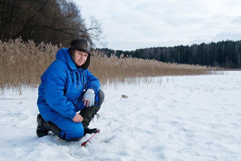 Pesca dell'uomo anziano sul lago al giorno di inverno freddo immagini stock libere da diritti Pesca dell'uomo anziano sul lago al giorno di inverno freddo immagini stock libere da diritti