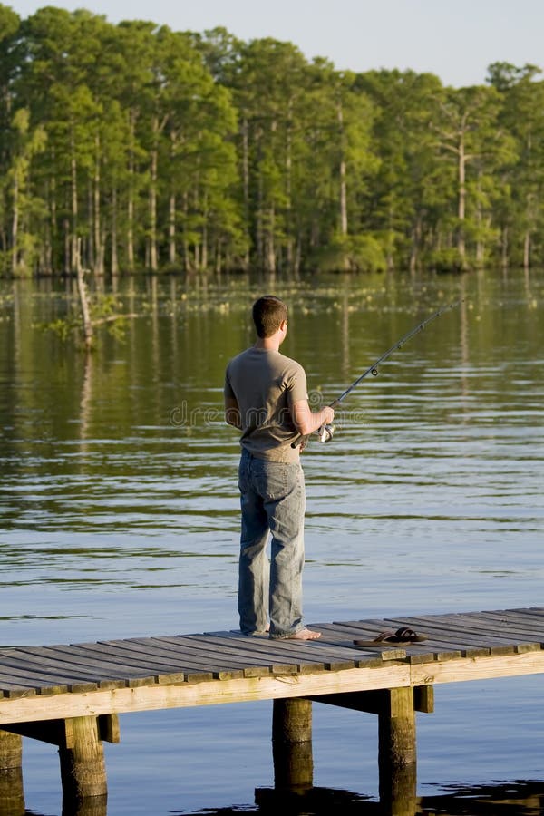 Pesca dell'uomo fuori da un bacino fotografia stock libera da diritti Pesca dell'uomo fuori da un bacino fotografia stock libera da diritti