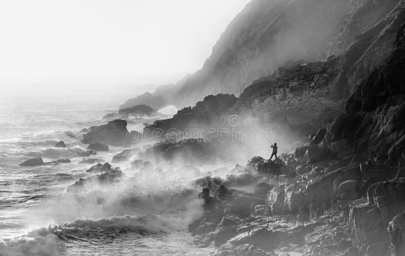 Pesca loca extrema en condiciones tormentosas en Porth Nanven en Cornwall. Olas y spray marino iluminado por el sol