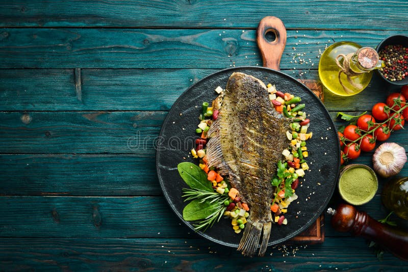 Pescado fresco al horno con verduras en placa de piedra negra. marisco. vista superior.