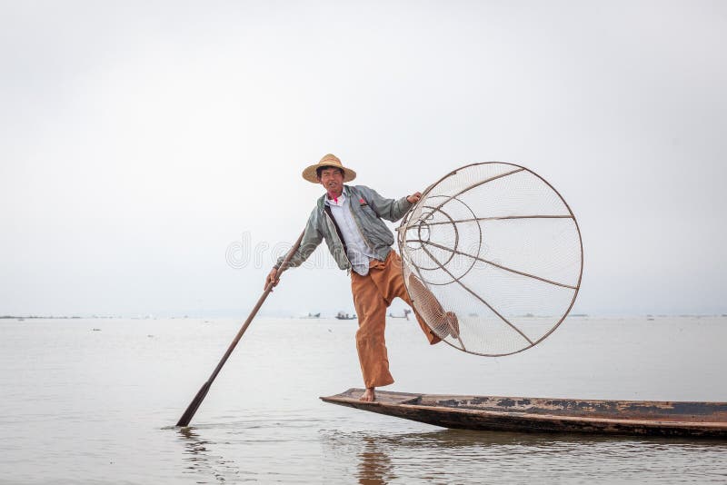 Pescador do birmanês que levanta para turistas em um barco de pesca tradicional no lago Inle, Myanmar Burma imagens de stock Pescador do birmanês que levanta para turistas em um barco de pesca tradicional no lago Inle, Myanmar Burma imagens de stock