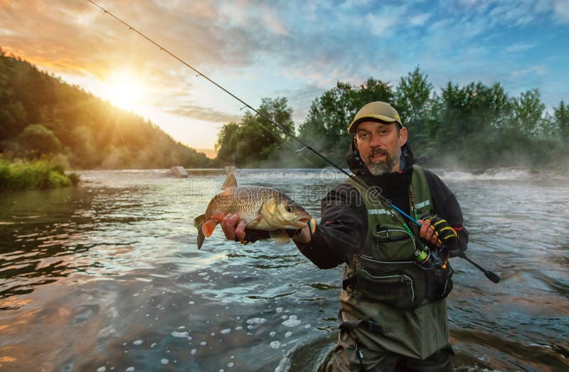 Pescador do esporte que guarda peixes do troféu Pesca exterior no rio