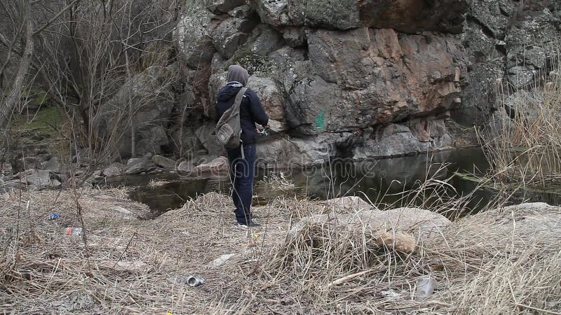 Pescador na margem do rio lança uma vara giratória com um girador