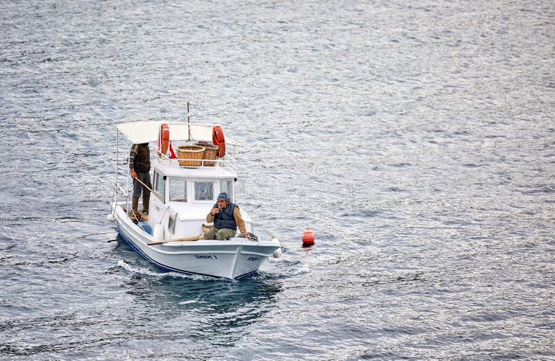 Pescador três turco masculino em uma navigação tradicional branca do barco de pesca sobre o mar em Gumusluk, Bodrum, Turquia foto de stock Pescador três turco masculino em uma navigação tradicional branca do barco de pesca sobre o mar em Gumusluk, Bodrum, Turquia foto de stock