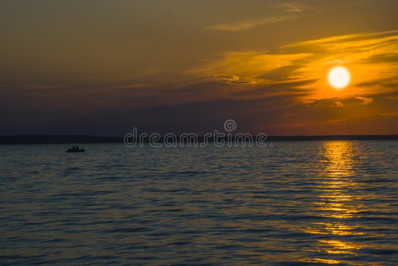 Pescadores no barco no lago no fundo do por do sol foto de stock Pescadores no barco no lago no fundo do por do sol foto de stock