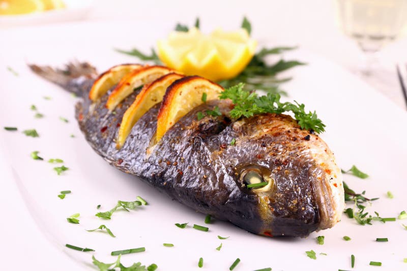 Pescados asados a la parrilla de la brema de mar, limón, arugula en la placa blanca fotografía de archivo libre de regalías Pescados asados a la parrilla de la brema de mar, limón, arugula en la placa blanca fotografía de archivo libre de regalías