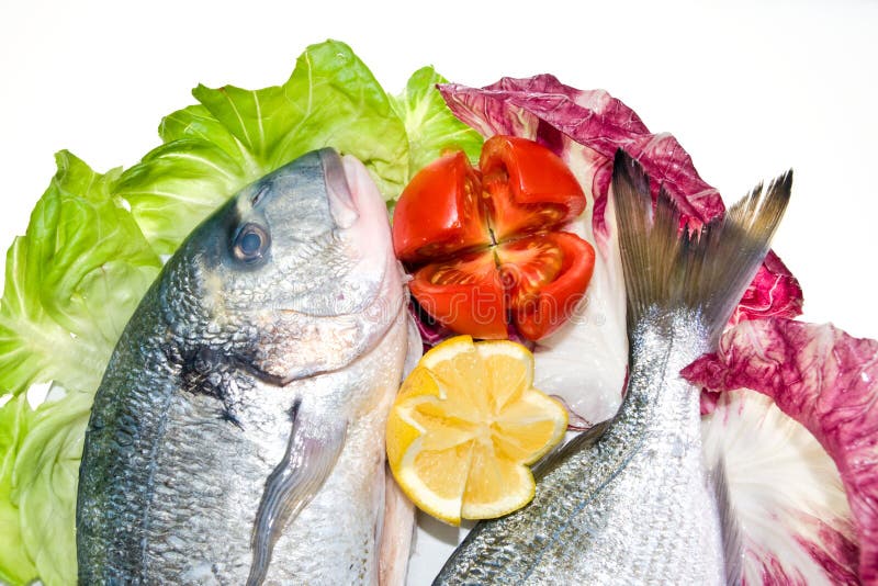 Pescados frescos con con la ensalada, el tomate y el limón. imagenes de archivo