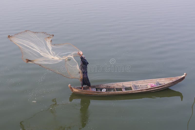 Pescatore birmano che getta una rete da pesca nel lago Taungthaman, Birmania fotografia stock Pescatore birmano che getta una rete da pesca nel lago Taungthaman, Birmania fotografia stock