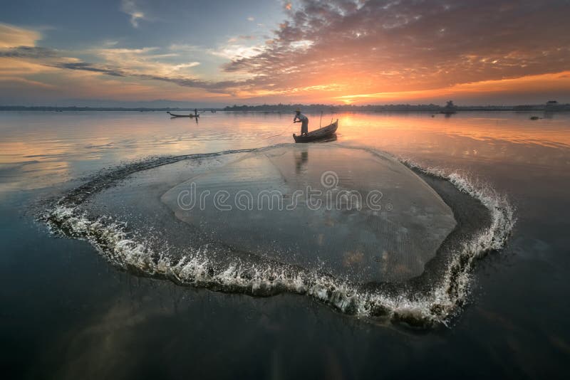 Pescatore che lancia la rete presto al mattino, Taung Tha Man Lake, Mandalay, Myanmar immagine stock libera da diritti Pescatore che lancia la rete presto al mattino, Taung Tha Man Lake, Mandalay, Myanmar immagine stock libera da diritti