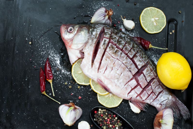 Pesce crudo con il limone, le erbe e le spezie su fondo d'annata scuro immagini stock libere da diritti Pesce crudo con il limone, le erbe e le spezie su fondo d'annata scuro immagini stock libere da diritti