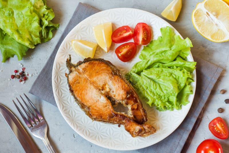 Pesce di color salmone al forno della bistecca su un piatto con gli ortaggi freschi fotografie stock Pesce di color salmone al forno della bistecca su un piatto con gli ortaggi freschi fotografie stock