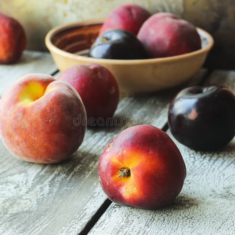 Pesche e prugne mature su un piatto su uno sfondo rustico fotografie stock Pesche e prugne mature su un piatto su uno sfondo rustico fotografie stock