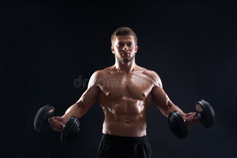 Pesi di sollevamento muscolari del giovane su fondo nero fotografie stock libere da diritti Pesi di sollevamento muscolari del giovane su fondo nero fotografie stock libere da diritti