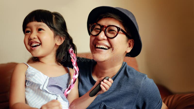 Pessoa Feliz, Uma Garota Bonita Sorrindo Sentada em Sofa com seu Pai Momento de felicidade por um grande sorriso de dentes fotos de stock Pessoa Feliz, Uma Garota Bonita Sorrindo Sentada em Sofa com seu Pai Momento de felicidade por um grande sorriso de dentes fotos de stock