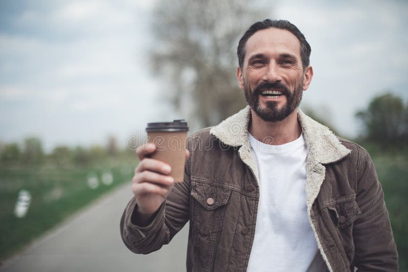 Pessoa masculina feliz que mantém o copo da bebida quente exterior fotos de stock Pessoa masculina feliz que mantém o copo da bebida quente exterior fotos de stock