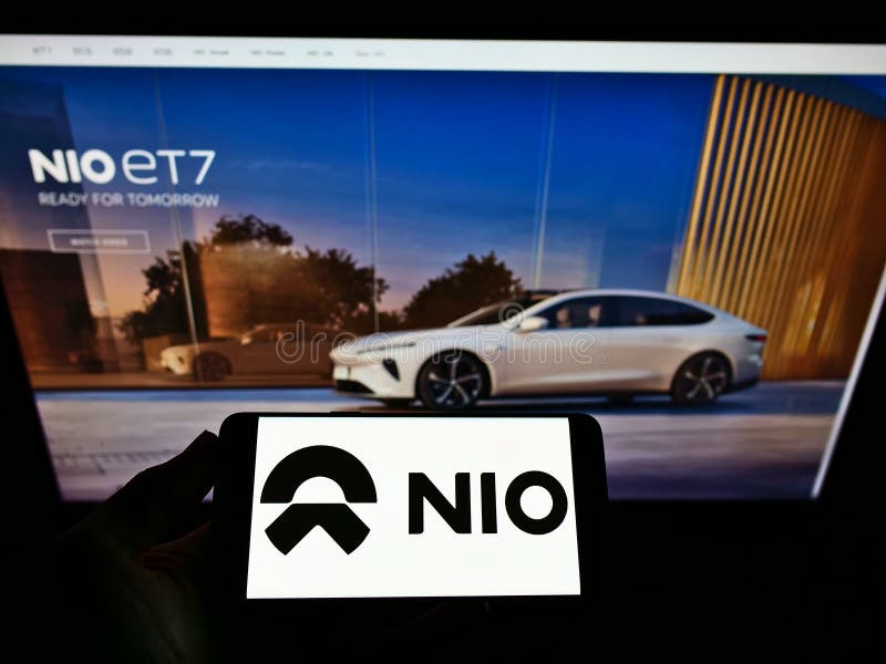 Pessoa segurando celular com logotipo comercial do fabricante chinês de automóveis elétricos. na tela em frente à página da Web.