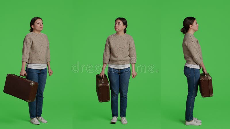 Casual person carrying vintage suitcase in studio, posing with broefcase on full body greenscreen backdrop. Female adult holding travel bag luggage on camera, standing over isolated green screen. Casual person carrying vintage suitcase in studio, posing with broefcase on full body greenscreen backdrop. Female adult holding travel bag luggage on camera, standing over isolated green screen.