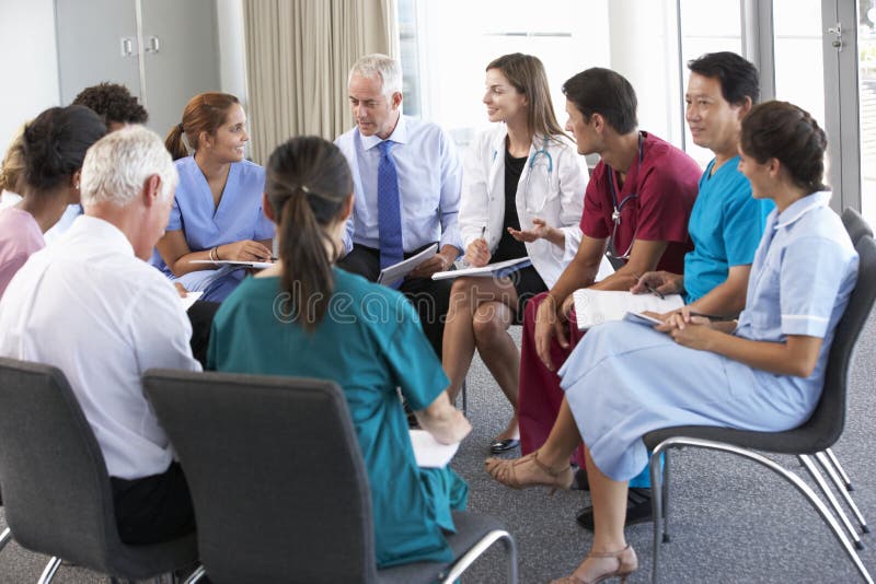 Pessoal médico assentado no círculo na reunião do caso imagem de stock Pessoal médico assentado no círculo na reunião do caso imagem de stock