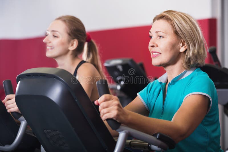 Pessoas idosas e jovens mulheres que dão certo no gym imagem de stock Pessoas idosas e jovens mulheres que dão certo no gym imagem de stock