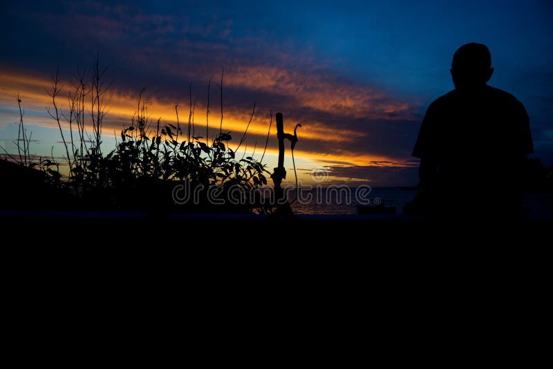 Pessoas não identificadas na silhueta desfrutando do lindo pôr de sol laranja dramático em uma praia fotos de stock royalty free