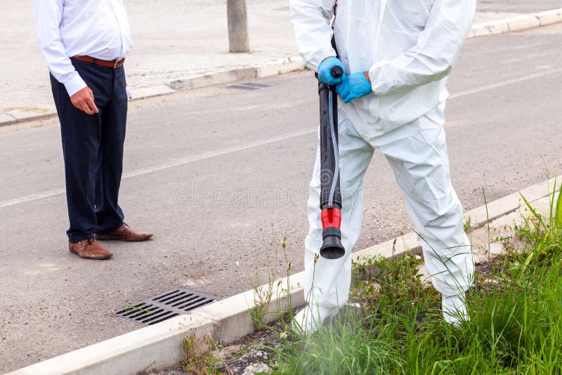 Man in Protective Workwear Spraying Herbicide on Ragweed in an Urban