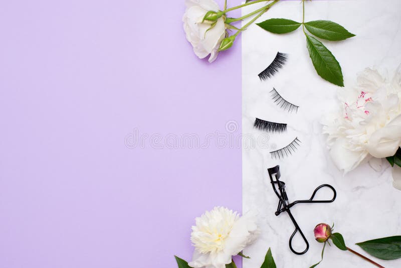 False eyelashes extensions black on white background with flowers, top view. Beauty concept. copy space. False eyelashes extensions black on white background with flowers, top view. Beauty concept. copy space.