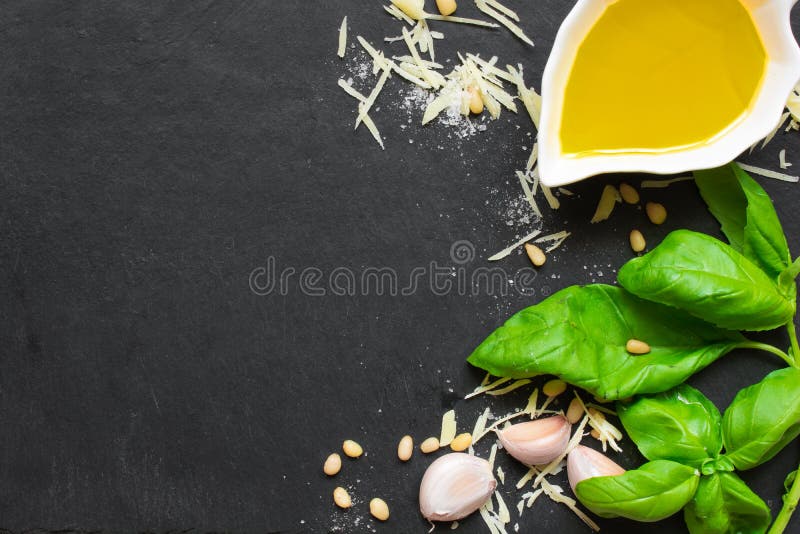 Pesto verde del basilico - ingredienti italiani di ricetta sul fondo nero della lavagna immagine stock Pesto verde del basilico - ingredienti italiani di ricetta sul fondo nero della lavagna immagine stock