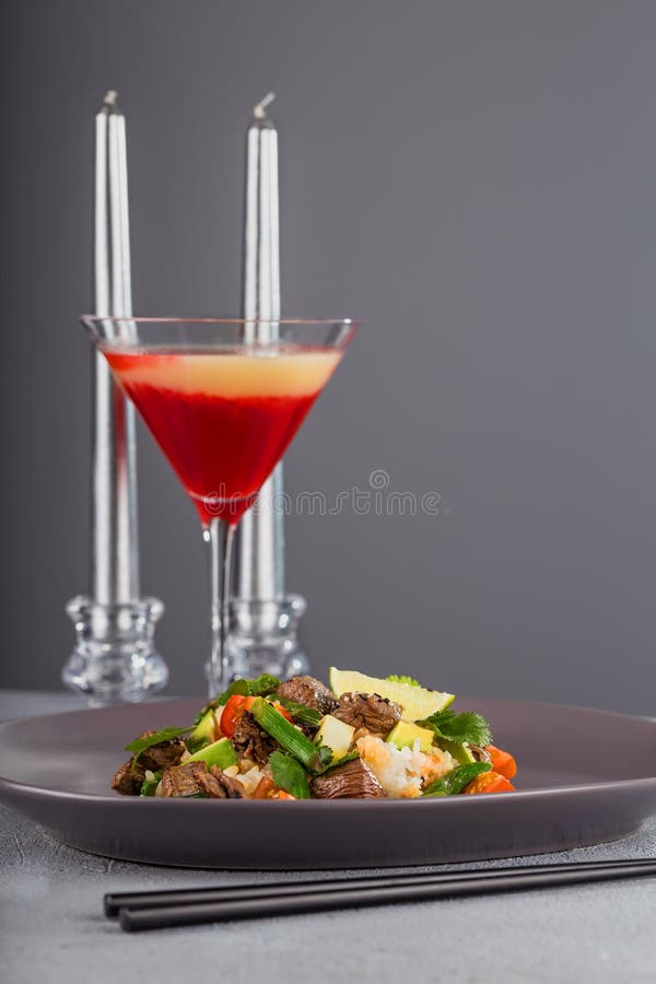 Peta med nötkött och ris på en härlig platta med stearinljus och ett exponeringsglas av drinken Hawaiansk kokkonst royaltyfria bilder Peta med nötkött och ris på en härlig platta med stearinljus och ett exponeringsglas av drinken Hawaiansk kokkonst royaltyfria bilder