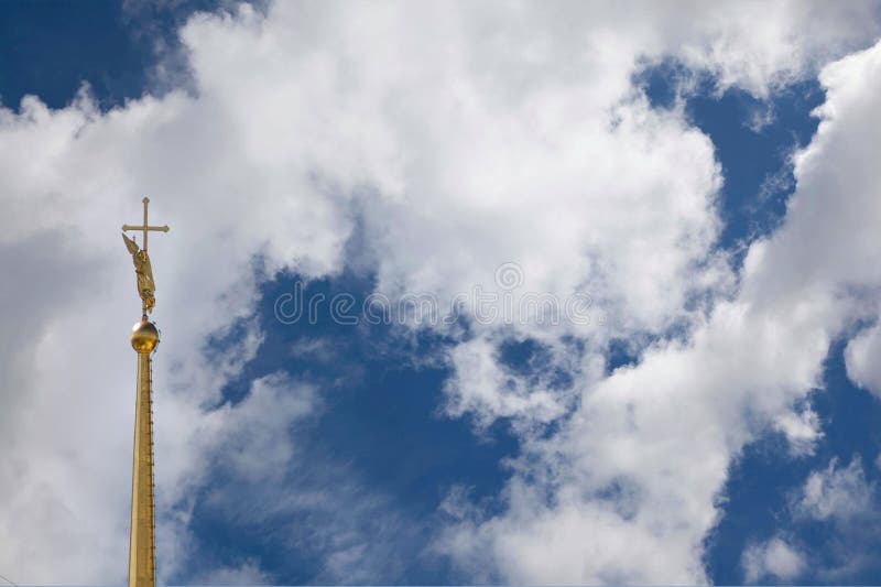 Magnificent view of the gilded spire of the Orthodox Cathedral in the city center with a figure of an angel in the form of a weather vane and an Orthodox cross, details and elements of architecture, cloudy sky, interesting background, city attractions, travel and tourism, summer. Magnificent view of the gilded spire of the Orthodox Cathedral in the city center with a figure of an angel in the form of a weather vane and an Orthodox cross, details and elements of architecture, cloudy sky, interesting background, city attractions, travel and tourism, summer.