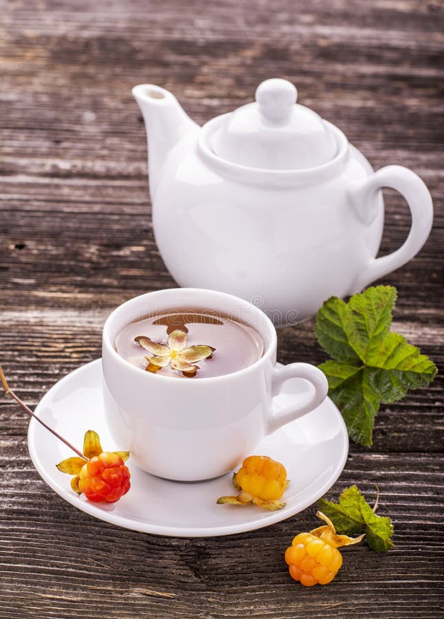 Petisco claro útil do café da manhã Chá erval fresco do fruto com bagas e os cloudberries nortes das folhas em um copo cerâmico b imagem de stock Petisco claro útil do café da manhã Chá erval fresco do fruto com bagas e os cloudberries nortes das folhas em um copo cerâmico b imagem de stock