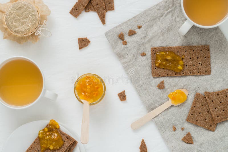 Petisco ou café da manhã doce com os biscoitos suecos do pão torrado do centeio, doce alaranjado da propagação, copos com chá ver imagens de stock Petisco ou café da manhã doce com os biscoitos suecos do pão torrado do centeio, doce alaranjado da propagação, copos com chá ver imagens de stock