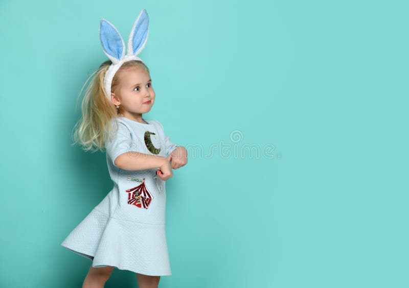 Petit bébé avec des oreilles de lapin sur ses sauts principaux comme un lapin sur le fond avec l'espace de texte libre photo libre de droits Petit bébé avec des oreilles de lapin sur ses sauts principaux comme un lapin sur le fond avec l'espace de texte libre photo libre de droits