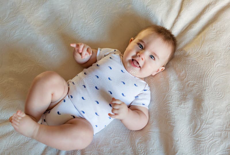 Petit bébé garçon très mignon se trouvant sur le lit sur le dos sur un ligh photo libre de droits Petit bébé garçon très mignon se trouvant sur le lit sur le dos sur un ligh photo libre de droits