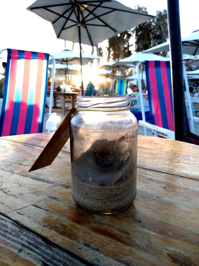 Petit conteneur en verre avec le sable de plage À l'arrière-plan un beau coucher du soleil photos stock Petit conteneur en verre avec le sable de plage À l'arrière-plan un beau coucher du soleil photos stock
